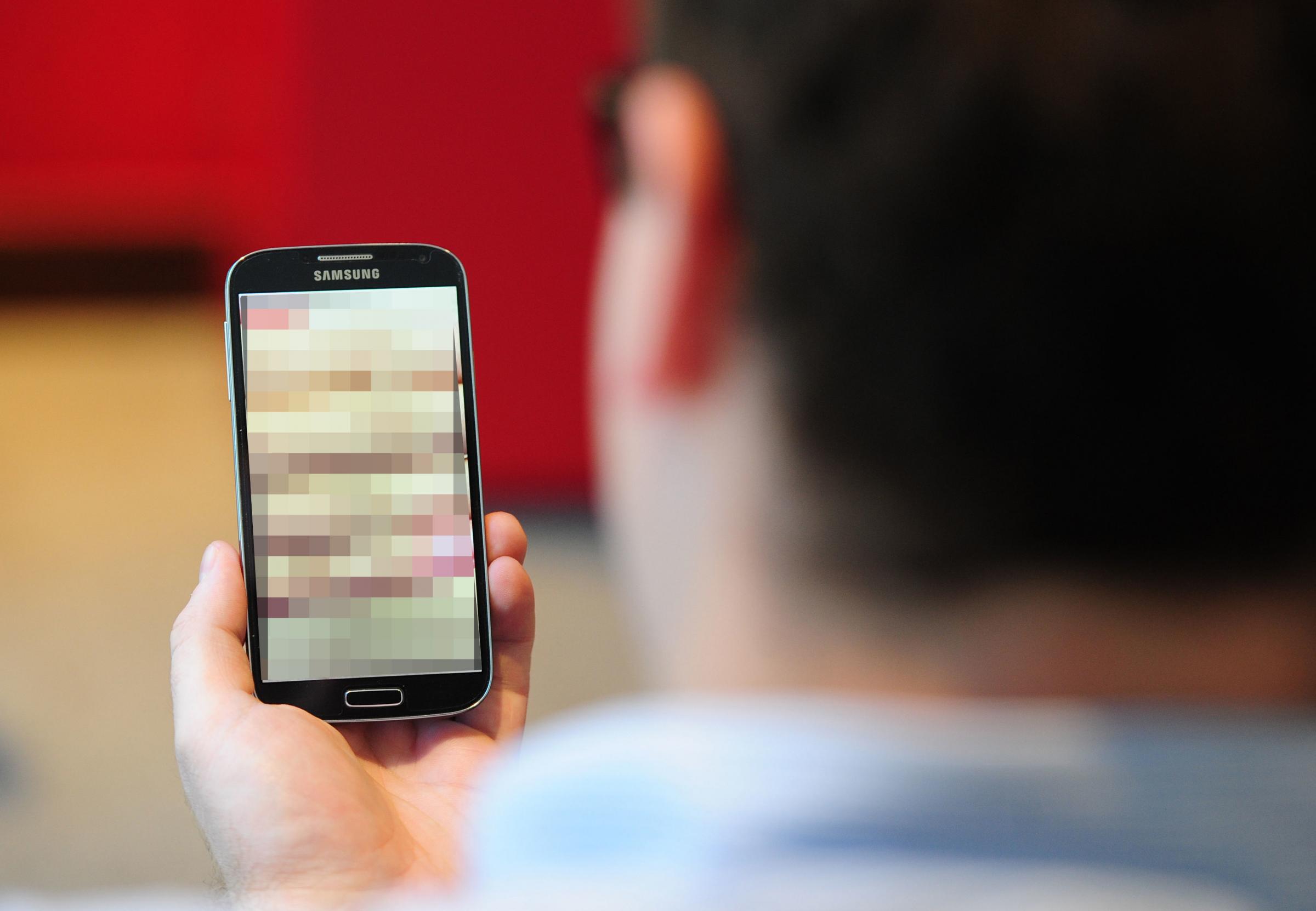 Embargoed to 0001 Monday July 01..PICTURE POSED BY MODEL.Undated photo of a man looking at a mobile phone. Women are being let down by lacklustre laws which are failing to protect them from image-based sexual abuse such as revenge porn and fake porn